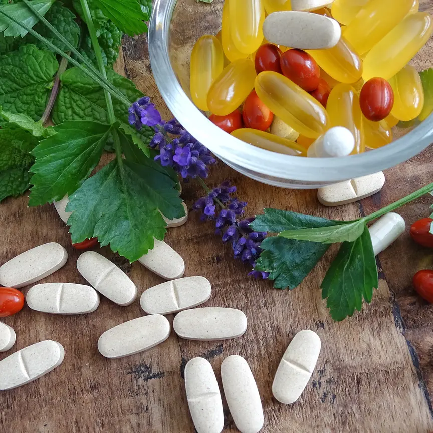 Comprimidos y cápsulas de suplementos junto a plantas medicinales