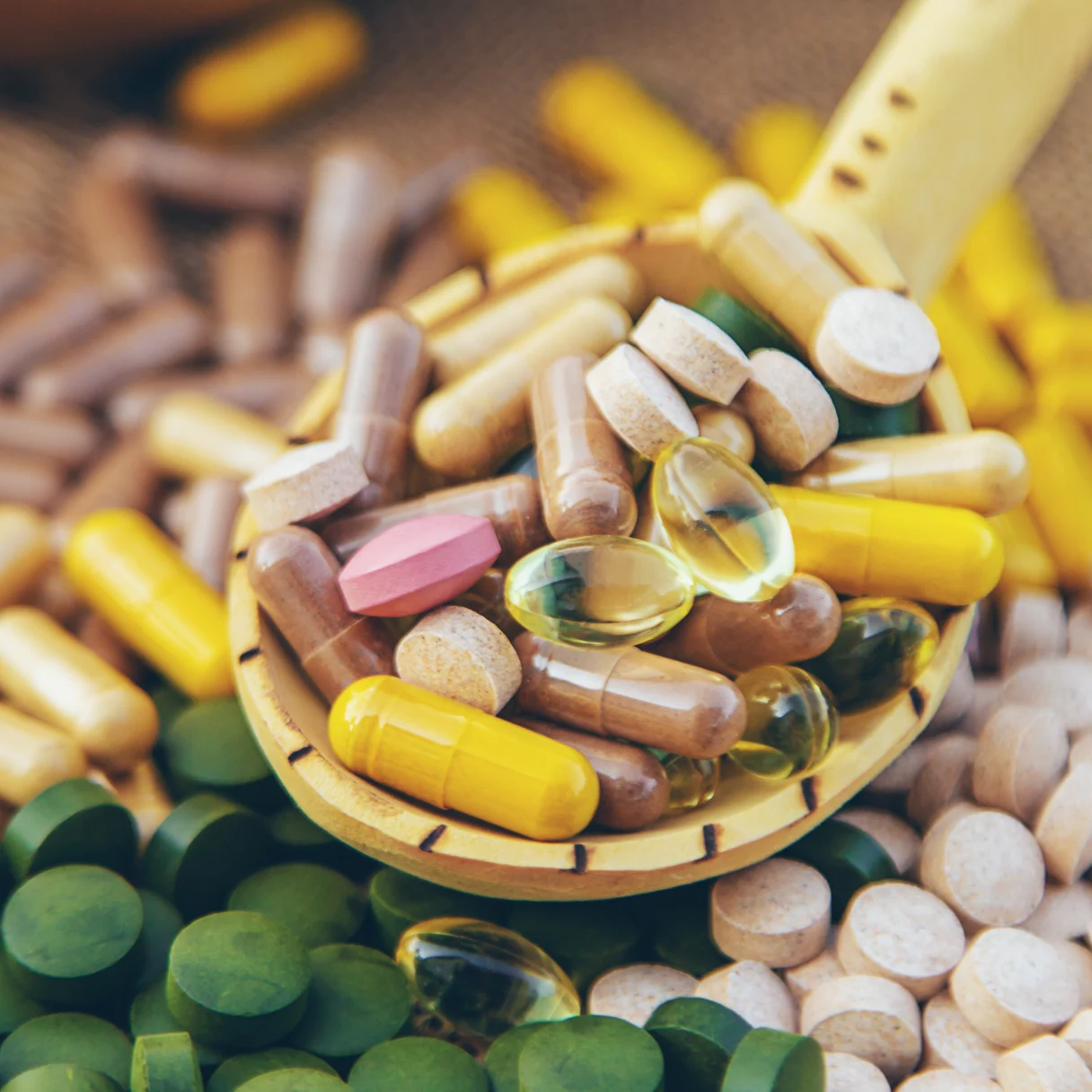 Cápsulas y comprimidos de espirulina en una cuchara de madera